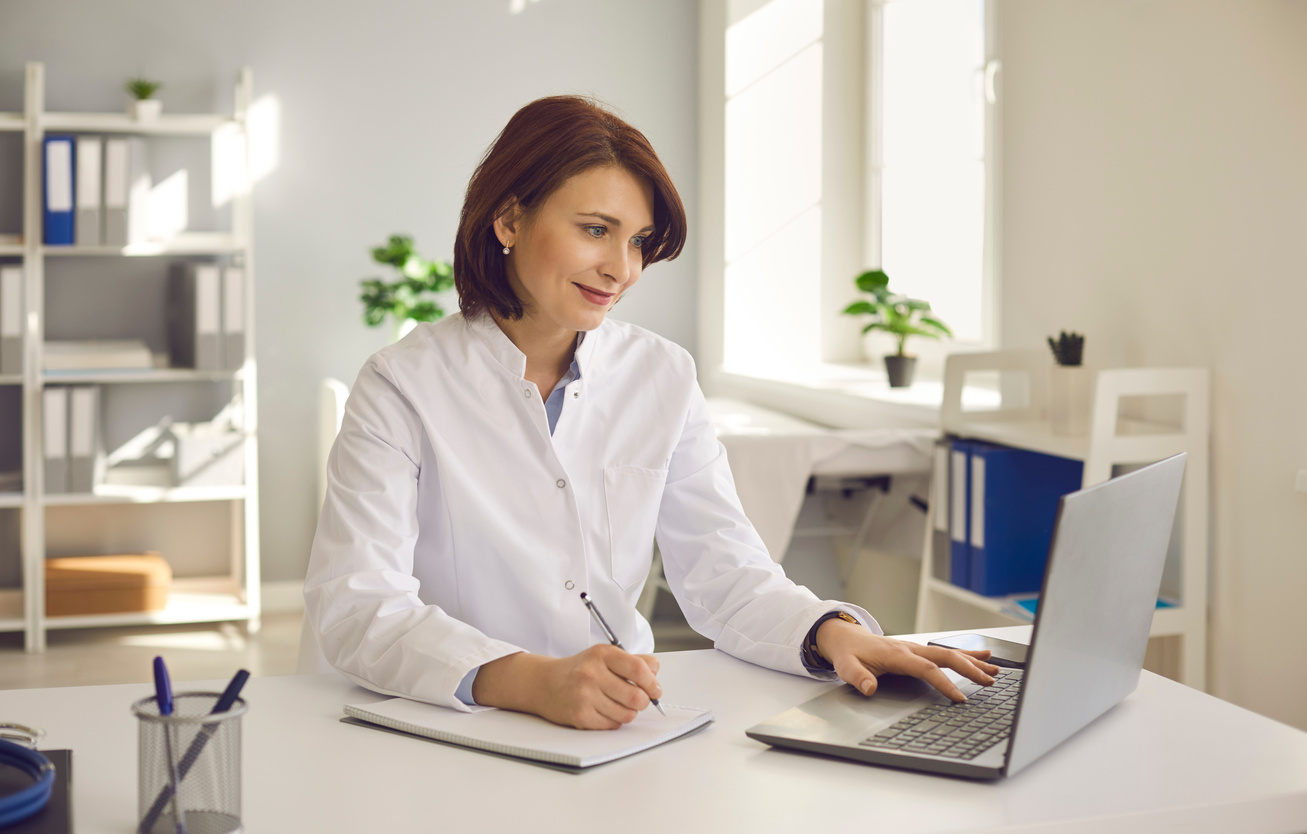 Female Doctor Writes Notes While Watching an Online Medical Webinar or Training Seminar.